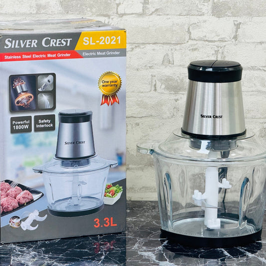 Silver Crest electric chopper in a 3.3 liter glass bowl, with packaging box and a manual, on a kitchen counter.